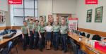 Grupa Funkcjonariuszy Celno - Skarbowych stoi w dwóch rzędach po bokach stoły  szkoleniowe